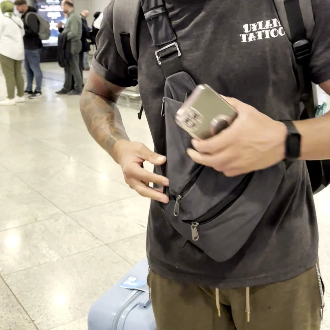 Taking a phone out of the top pocket of the gray FlyHugz Anti-Theft Bag