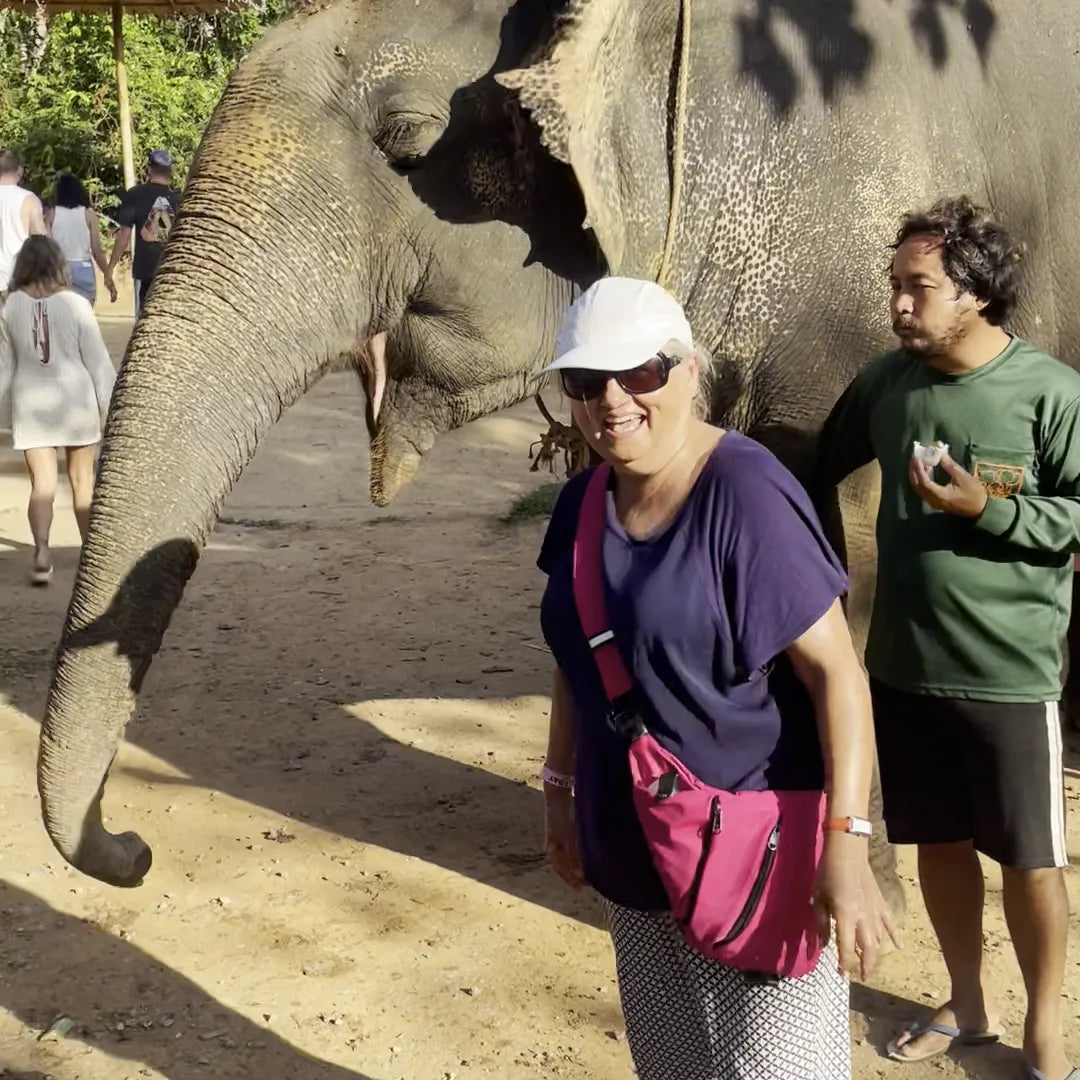 A traveler in her 60s wearing the pink FlyHugz Anti-Theft Bag in front
