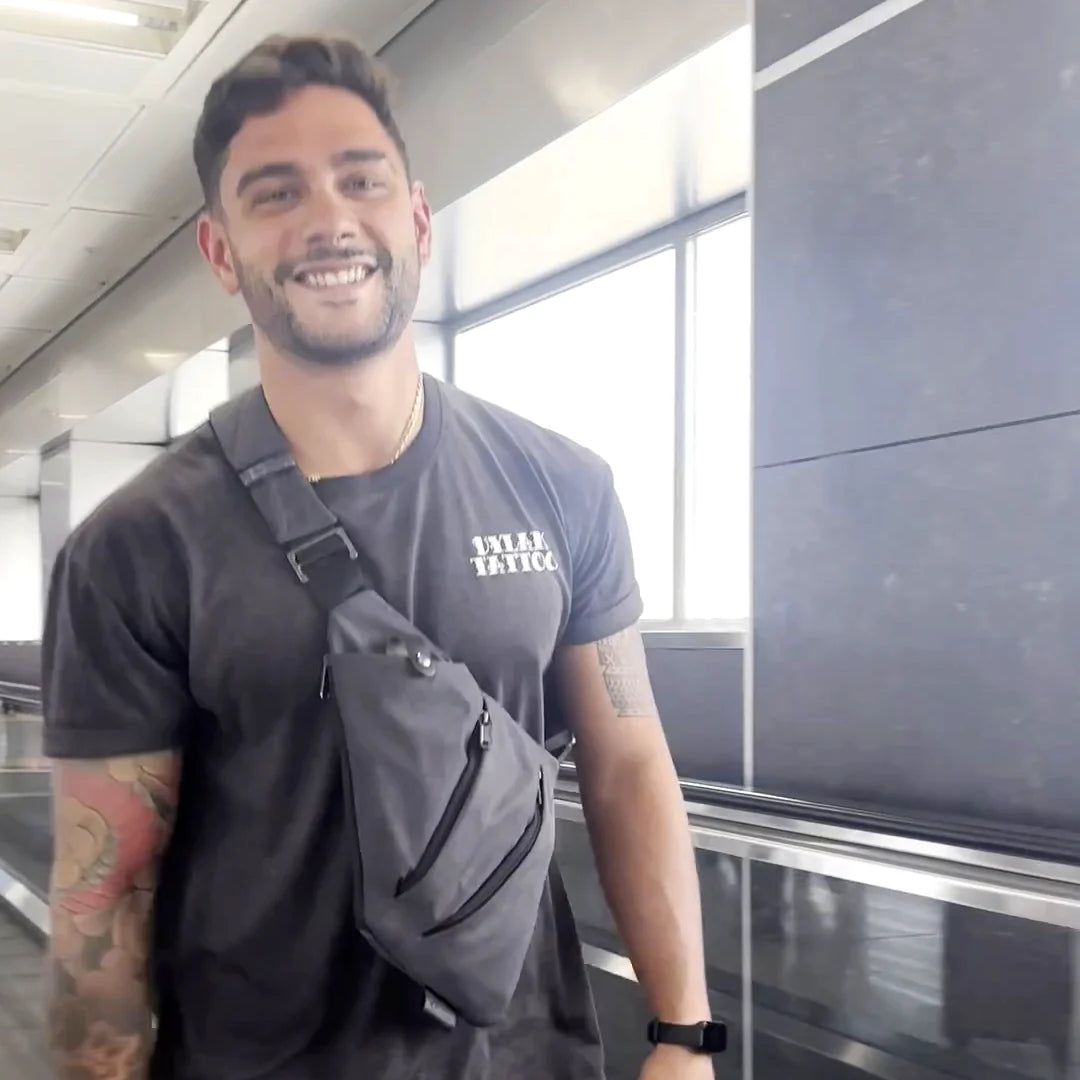 A traveler walking through the airport with the gray FlyHugz Anti-Theft Bag across his chest