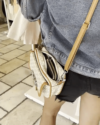 A hand sliding a wallet out of a shoulder purse